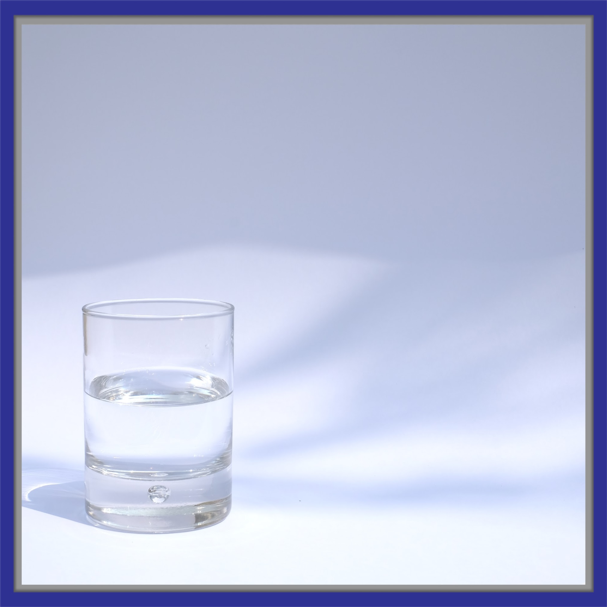 image of a mostly full water glass against a gray blue background