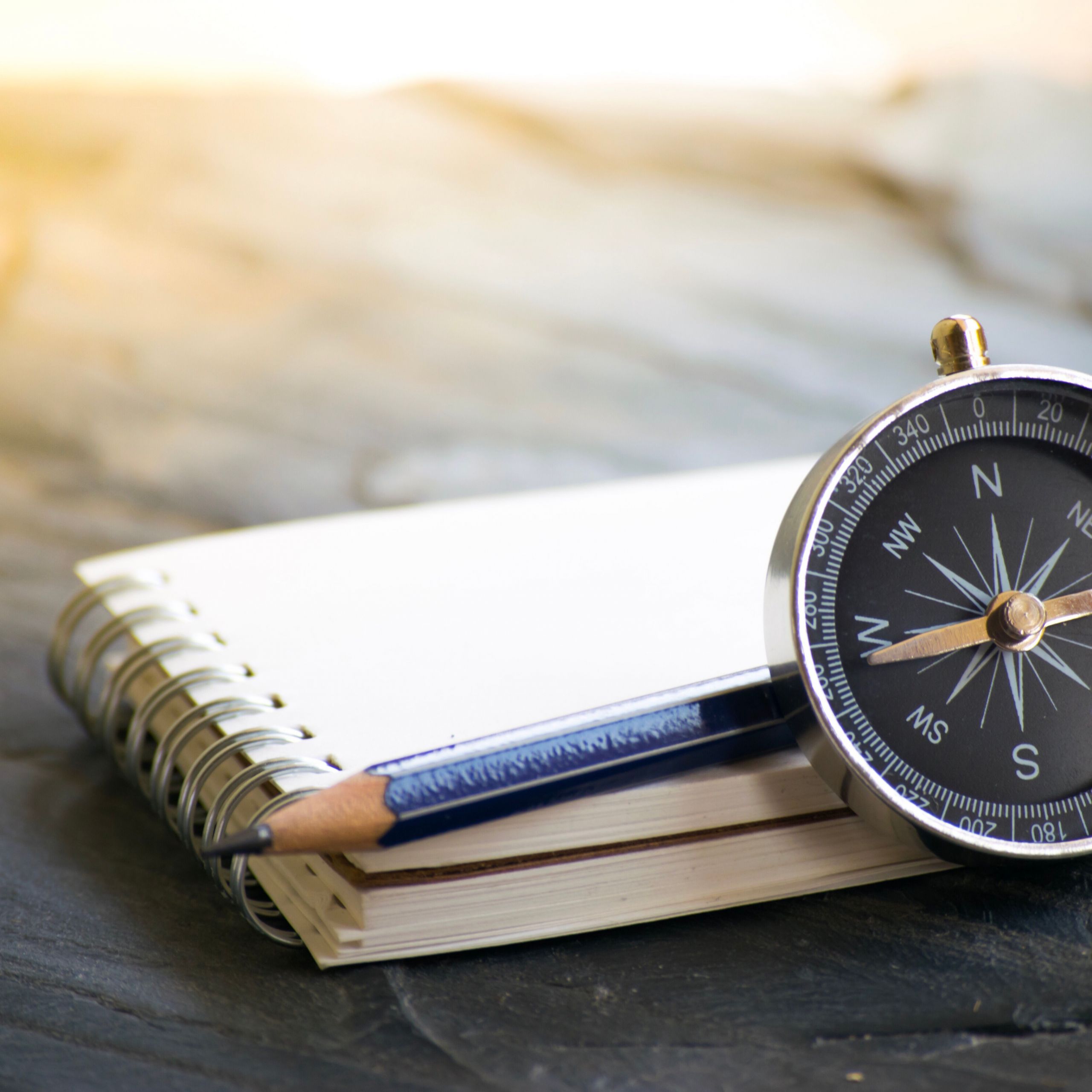 A notebook, pencil, and compass lying together on a wooden table