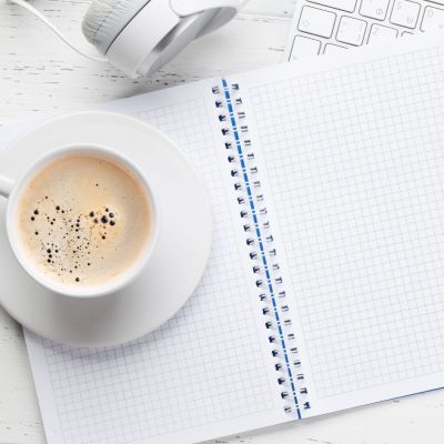 A hot beverage in a cup and a gridded notebook.
