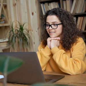 A young person resting her head on her hands while learning online.