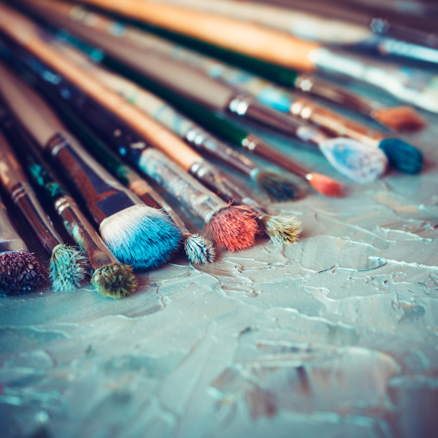 A variety of paint brushes spread across a canvas