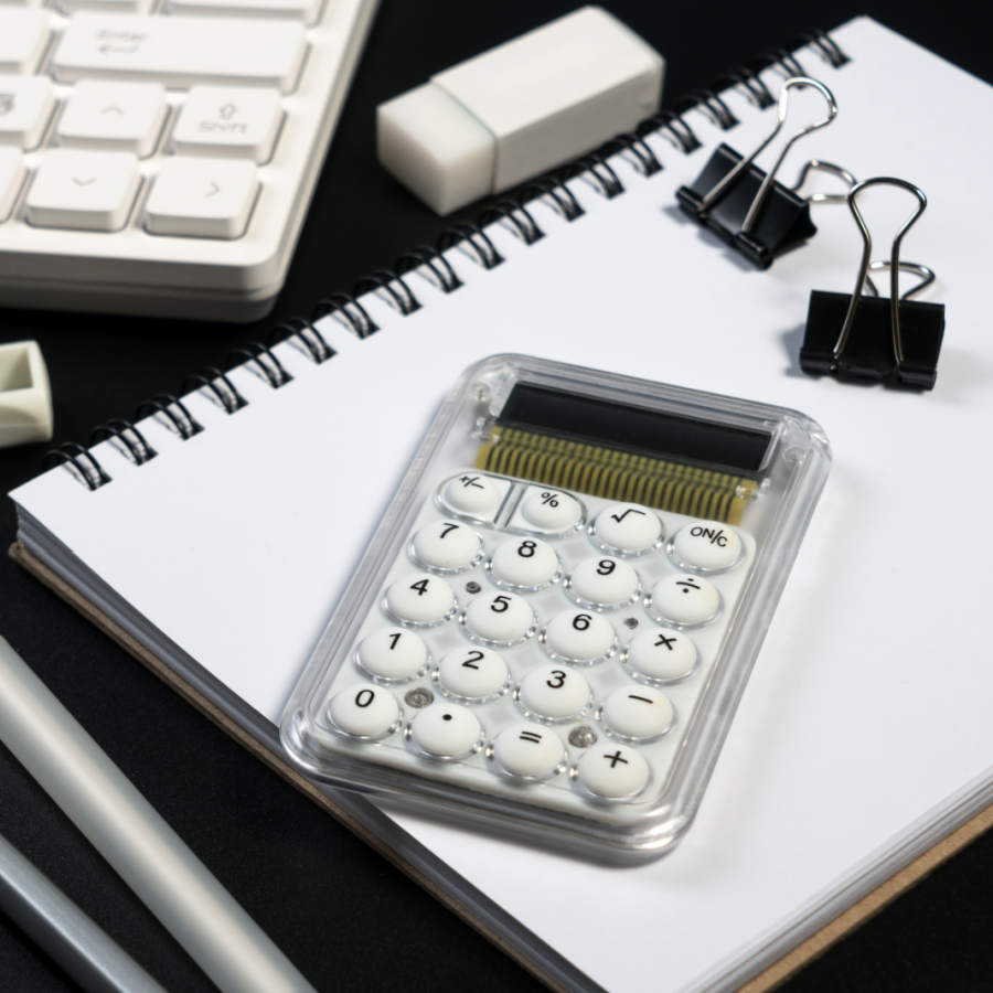 A keyboard, notebook, calculator, pen, eraser, and clips in shades of black and white